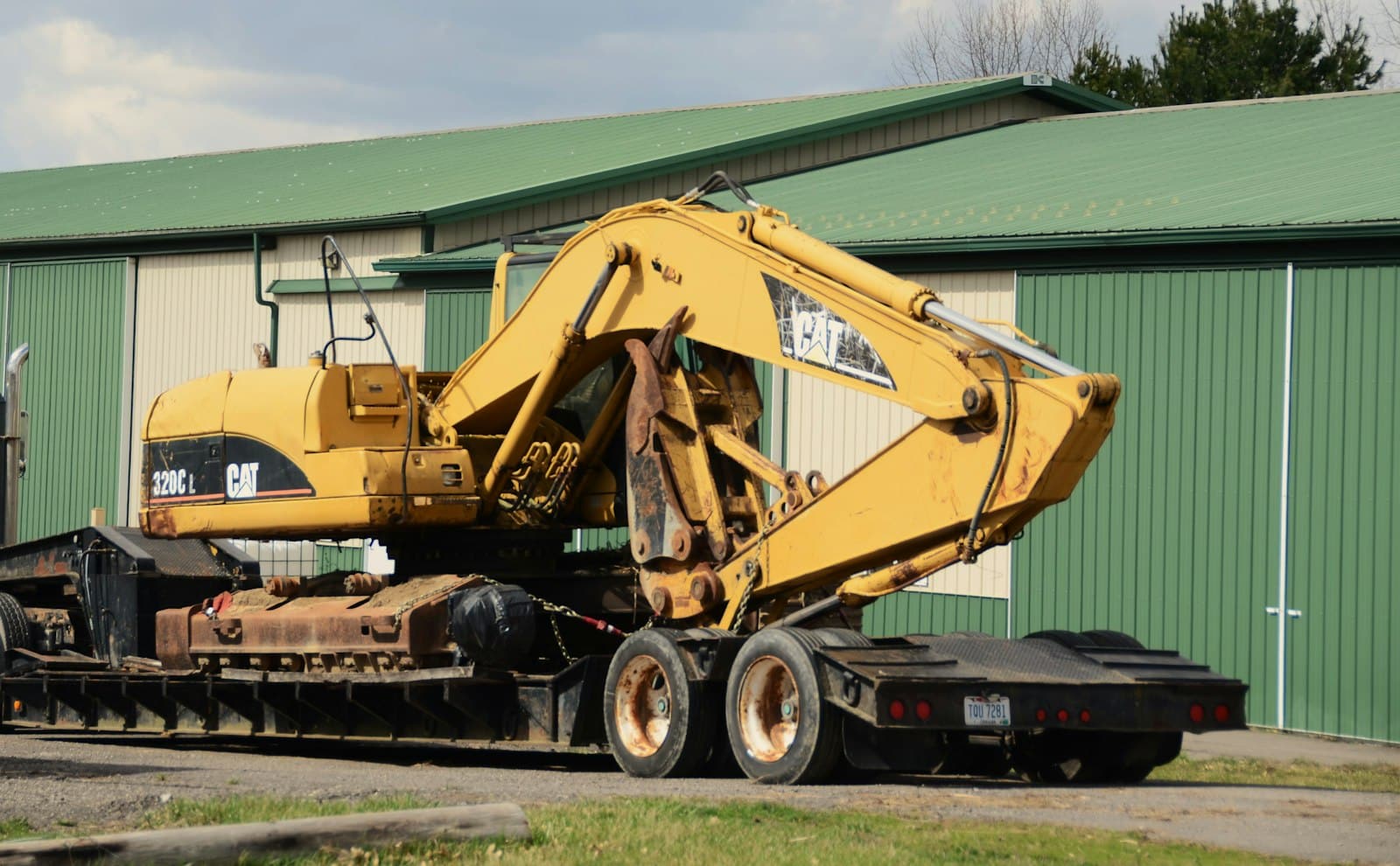 A yellow excavator chained down on a flatbed trailer deck.